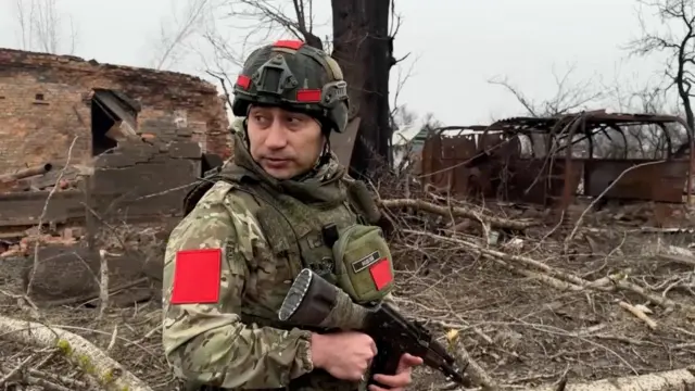 A Russian army soldier stands in a ruined street in Kursk