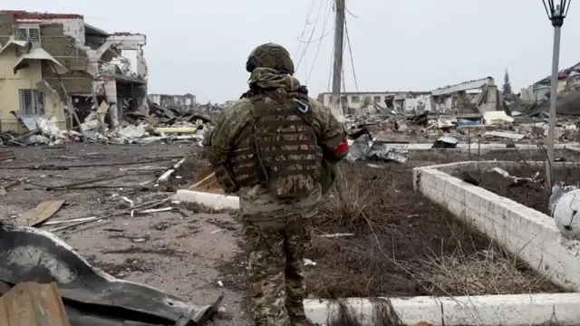 A Russian army soldier walks along a ruined street in Kursk
