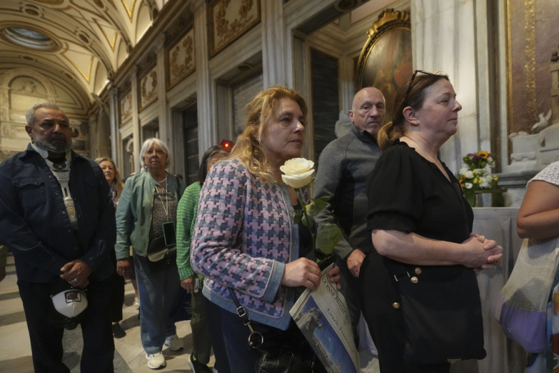 A woman holds a white rose as she waits in line to pay her respects to the tomb of Pope Francis inside St. Mary Major Basilica in Rome