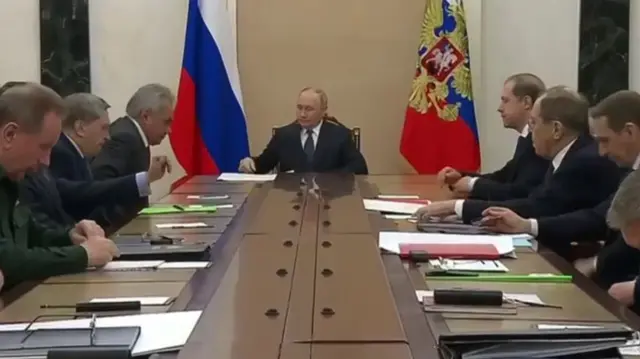 Putin sitting at the head of a table with Russian officials and generals. Among them are FM Lavrov, defence minister Andrei Belousov, National Guard commander Viktor Zolotov, chief of the General Staff Valery Gerasimov, and FSB chief Alexander Bortnikov