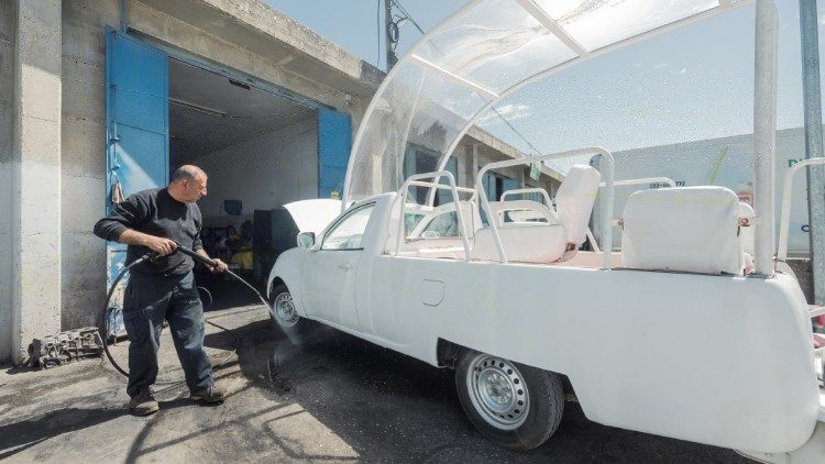Men work on turning the popemobile into a health clinic