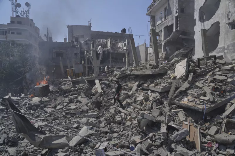 A Palestinian man walks across the rubble of a building destroyed by an Israeli strike in Deir al-Balah, central Gaza Strip, Monday